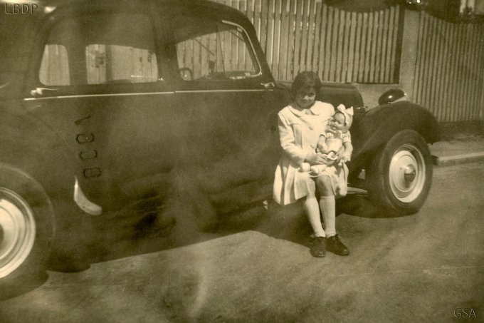 26 - Stihlé Angèle avec sa poupée Marguerite, assise sur le marche-pied d'une Citroën Traction